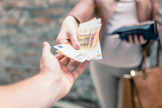 Seorang wanita menyerahkan sejumlah uang kepada seseorang dalam sebuah transaksi